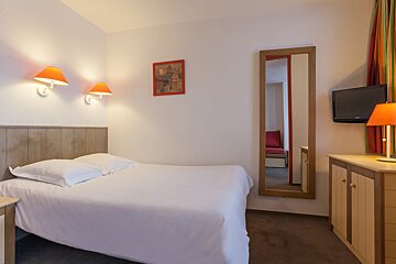 A hotel room with a bed and a television
