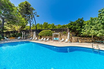 A large swimming pool surrounded by chairs and umbrellas