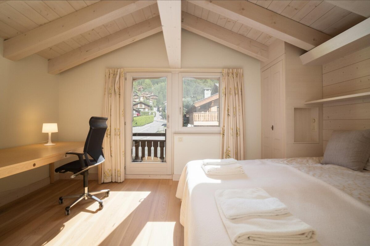 A bedroom with a bed a desk and a chair