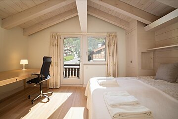 A bedroom with a bed a desk and a chair