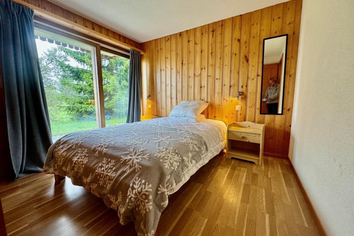 A bedroom with a bed a nightstand and a mirror