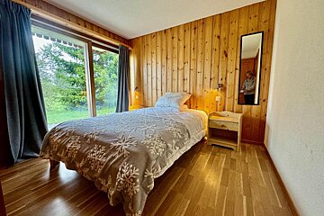 A bedroom with a bed a nightstand and a mirror