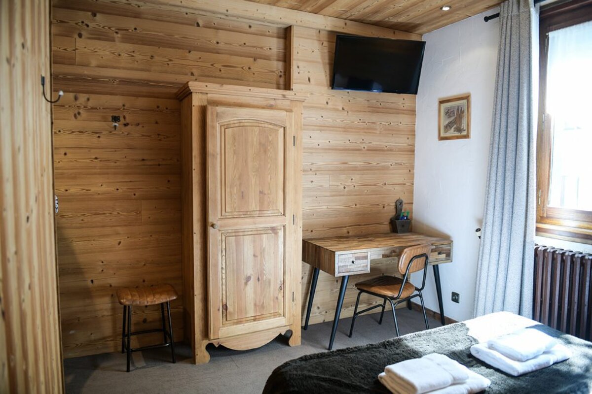 A wooden room with a desk and a television