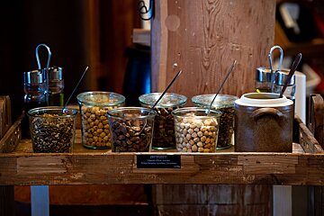 A wooden tray filled with jars of nuts including chickpeas