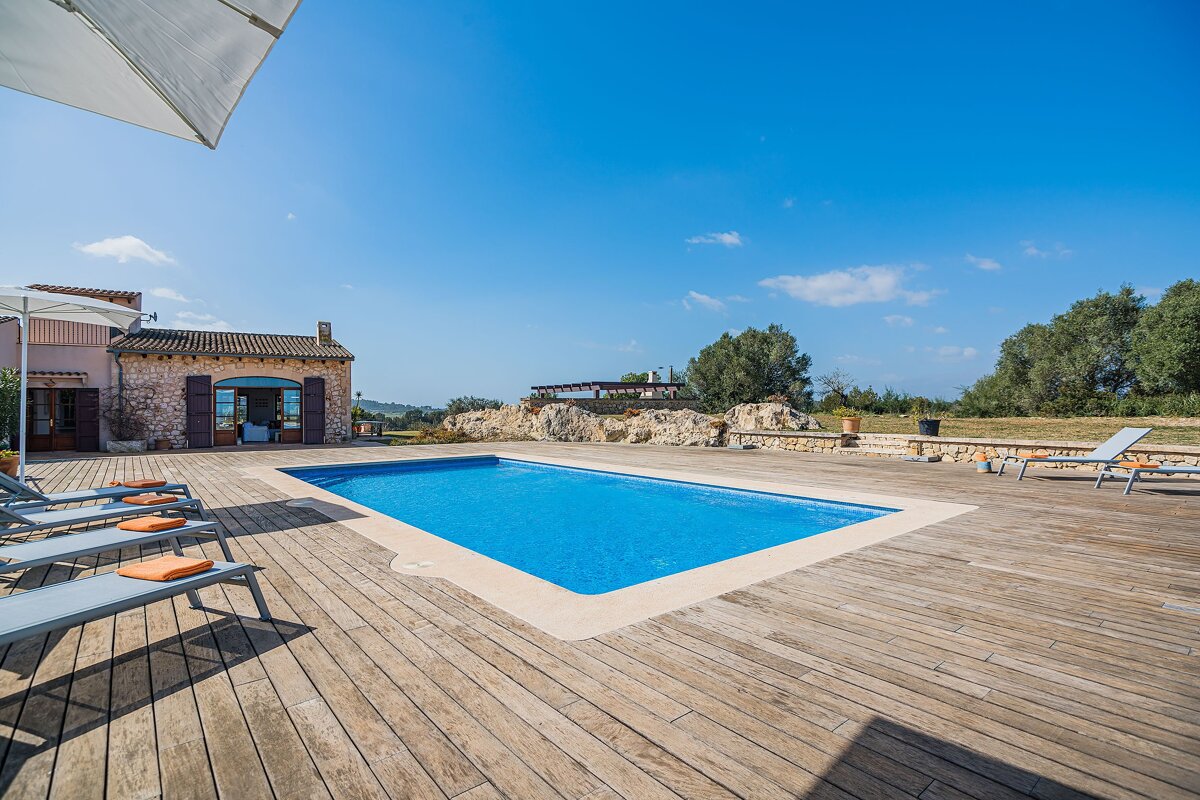 A large swimming pool is surrounded by a wooden deck