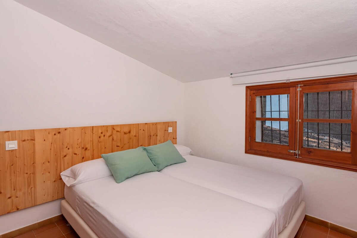 A bedroom with two beds and a wooden headboard