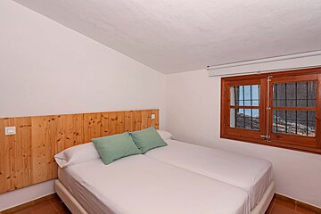 A bedroom with two beds and a wooden headboard