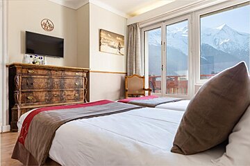 A hotel room with two beds a dresser and a flat screen tv