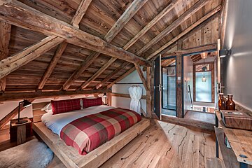 A bedroom with a wooden ceiling and a bed