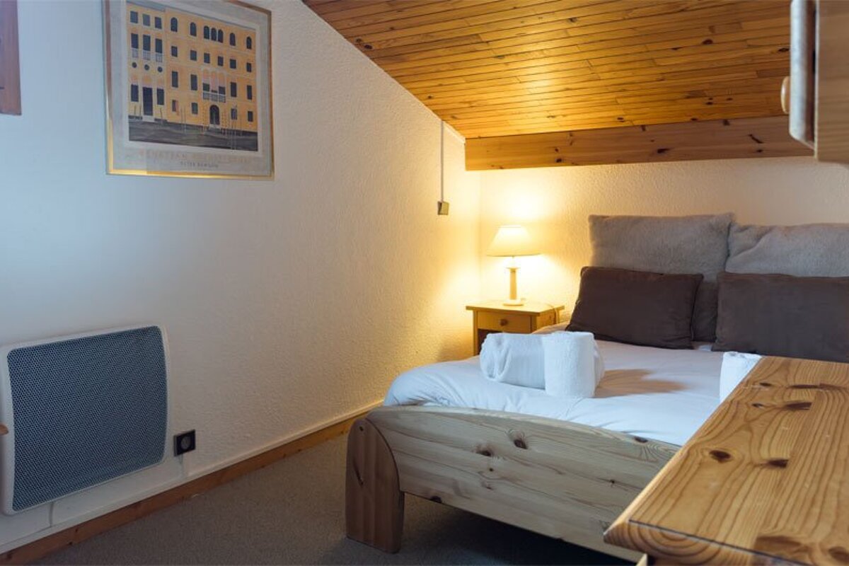 A bedroom with a bed and a picture of a building on the wall