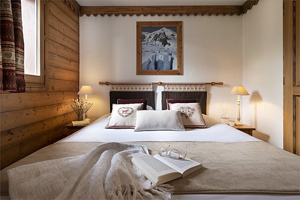 A bedroom with a picture of a mountain on the wall above the bed