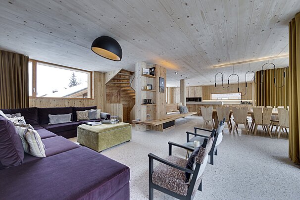 A living room with a purple sectional and a green ottoman