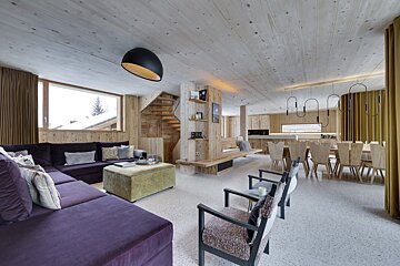 A living room with a purple sectional and a green ottoman
