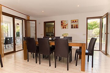 A dining room with a table and chairs and a painting on the wall