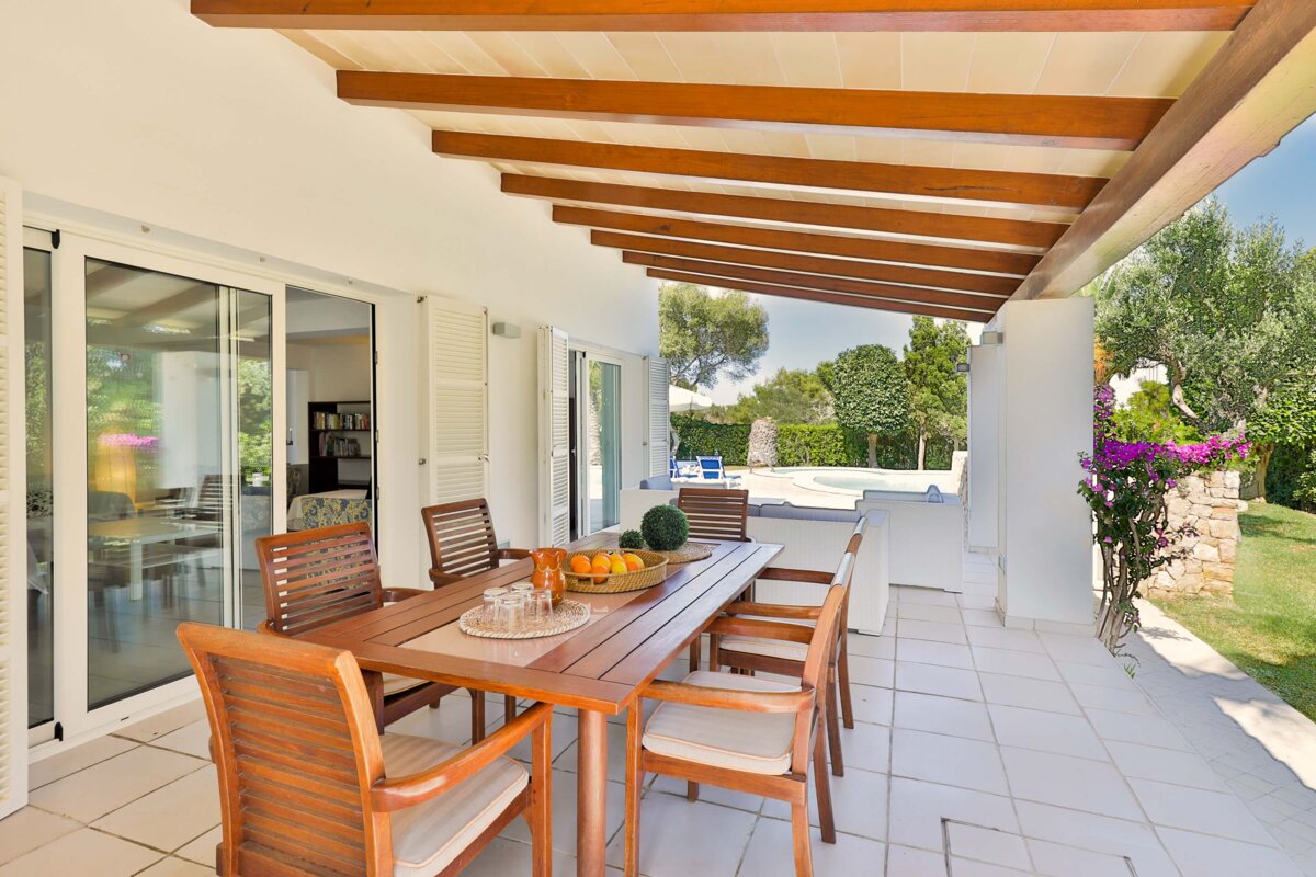 A patio with a table and chairs and a bowl of oranges on it