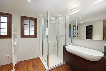 A bathroom with a walk in shower and a sink
