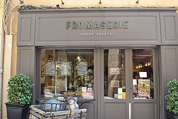 image of a fromageries shop front in Aix with a window display and hedges out front