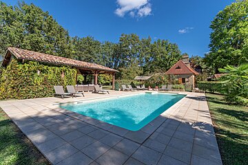 A large swimming pool surrounded by chairs and a gazebo