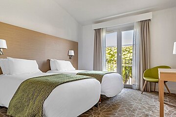 A hotel room with two beds and a green chair