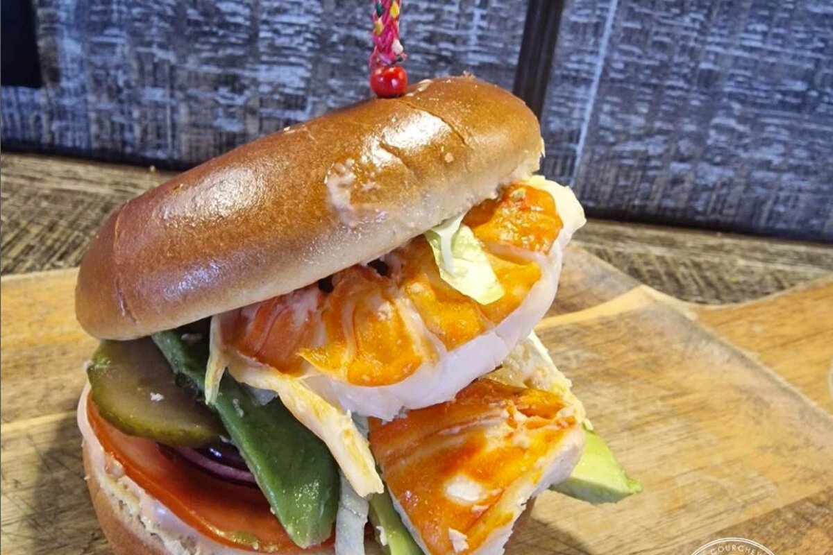 A sandwich from the burger factory sits on a wooden cutting board