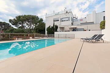 A large swimming pool in front of a building with a for sale sign