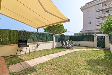 A fenced in yard with lawn chairs and a grill