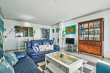 A living room with a blue couch and a glass coffee table