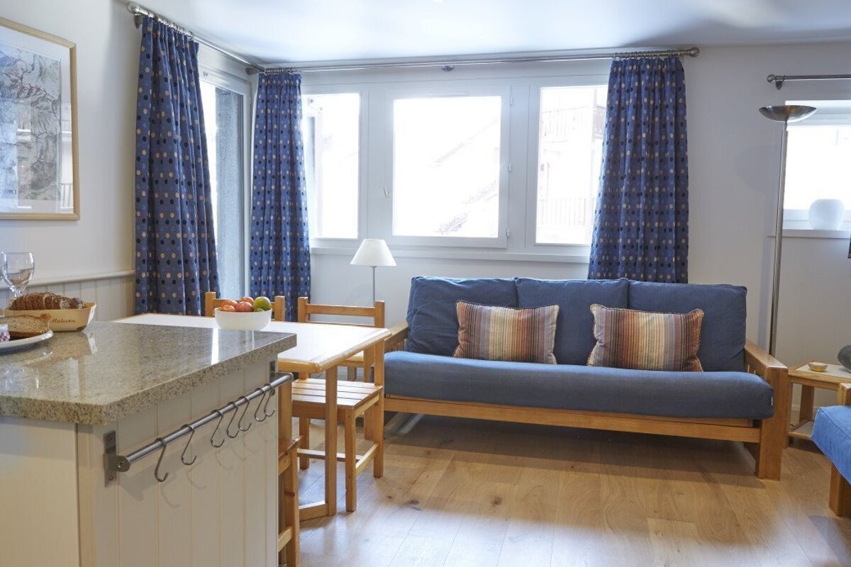 A living room with a blue couch and a bottle of wine