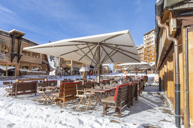 A snowy patio area with tables and chairs under umbrellas