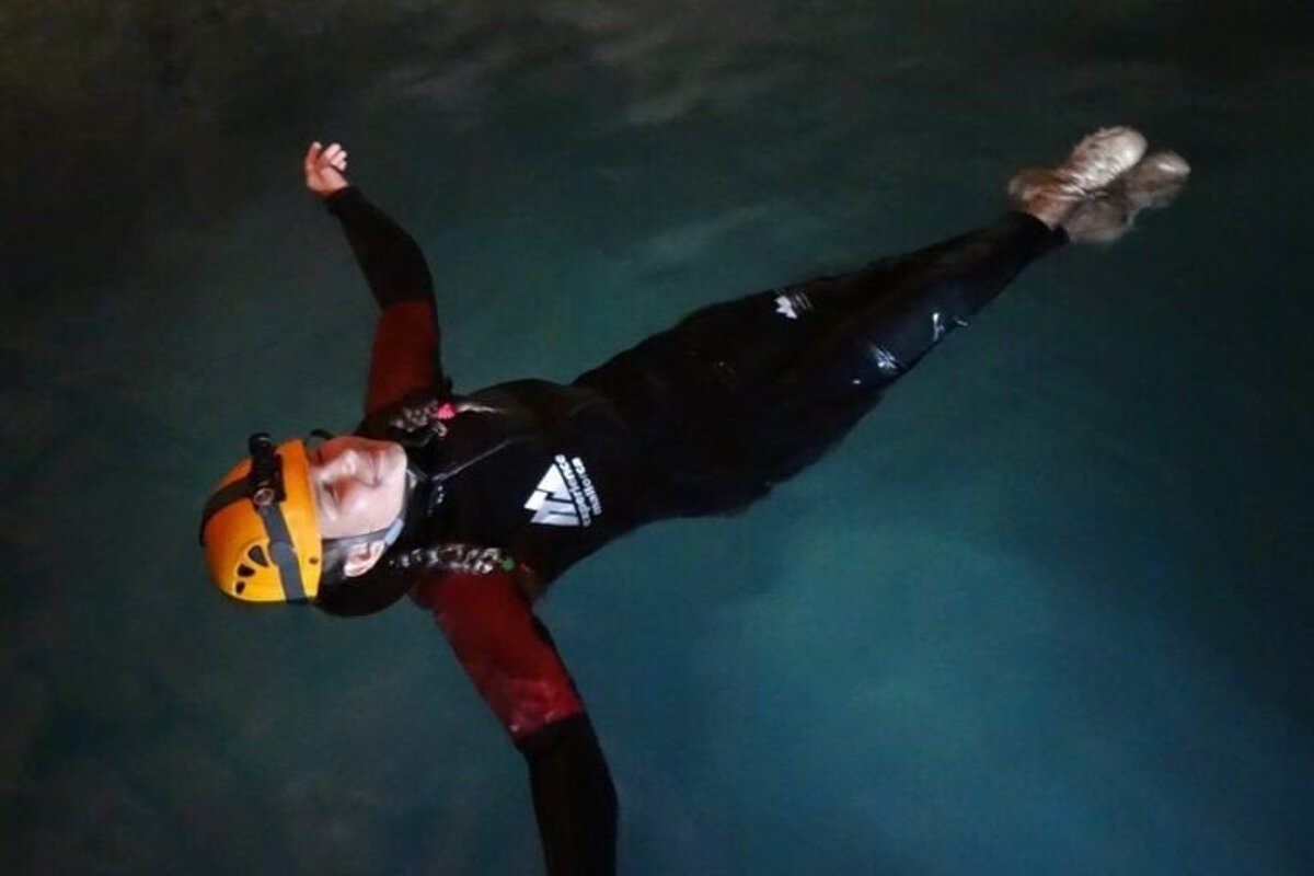 A person wearing a wetsuit and a helmet is floating in the water