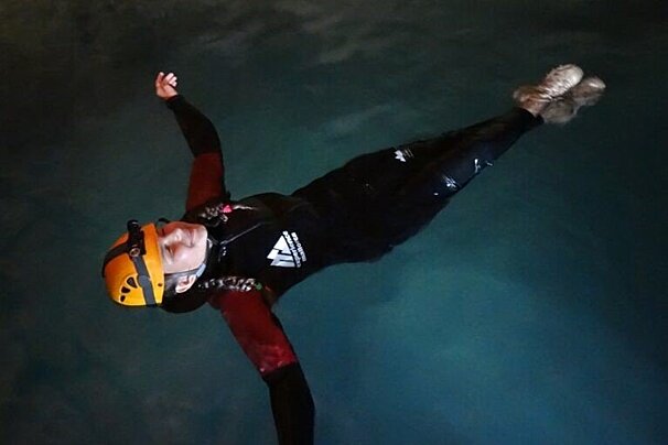 A person wearing a wetsuit and a helmet is floating in the water