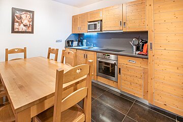 A kitchen with wooden cabinets and a picture of cows on the wall