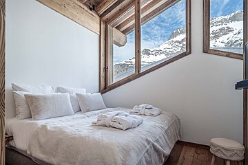 A bed in a room with a view of snowy mountains
