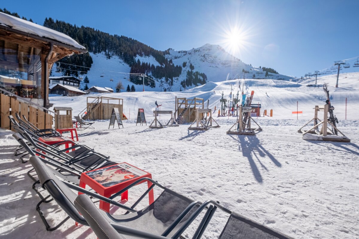 A row of chairs in the snow with a red table that says ' coca cola ' on it