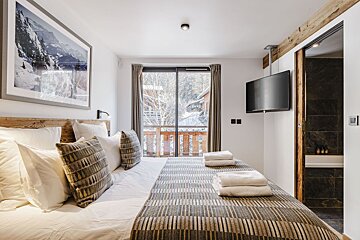 A bedroom with a large bed and a flat screen tv