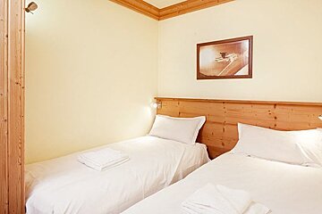 A bedroom with two beds and a picture on the wall