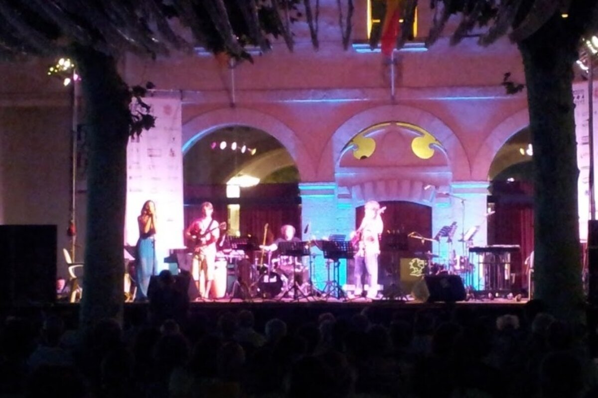 A group of people playing instruments on a stage in front of a crowd