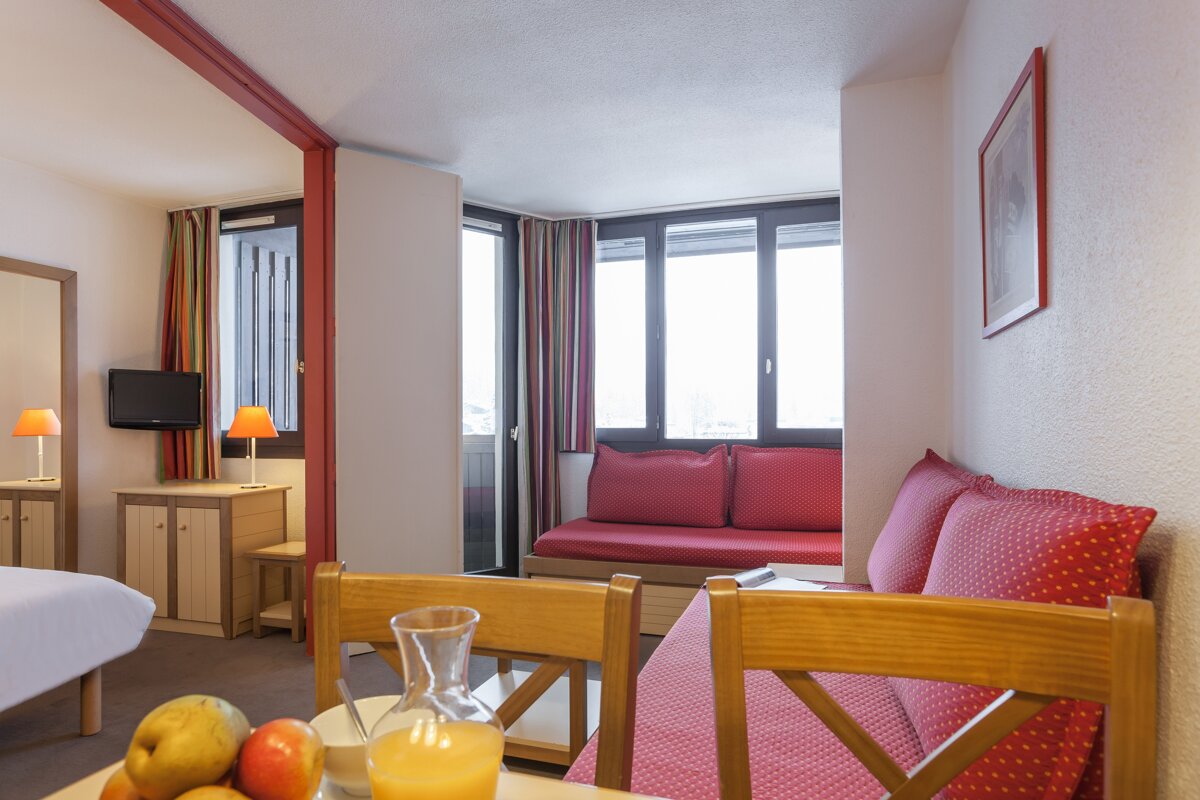 A room with a couch and a table with a pitcher of orange juice on it