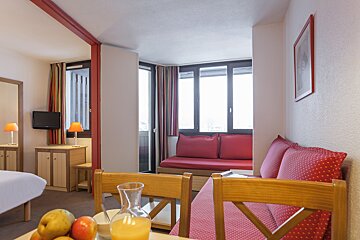 A room with a couch and a table with a pitcher of orange juice on it