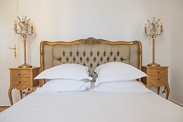 A bed with white sheets and a gold headboard