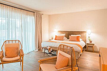 A bedroom with a large bed and two chairs