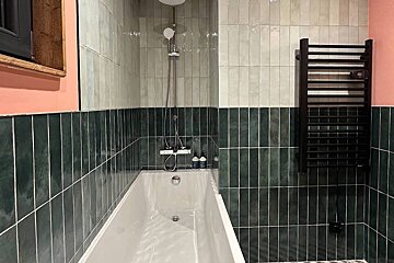 A bathroom with green and white tiles and a bathtub