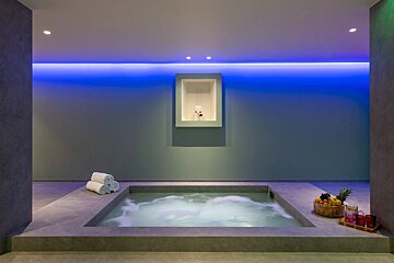 A jacuzzi in a room with blue lights on the wall