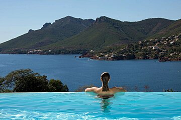 A woman is swimming in a pool with mountains in the background