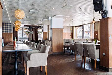 A restaurant with tables and chairs and a speaker on the ceiling