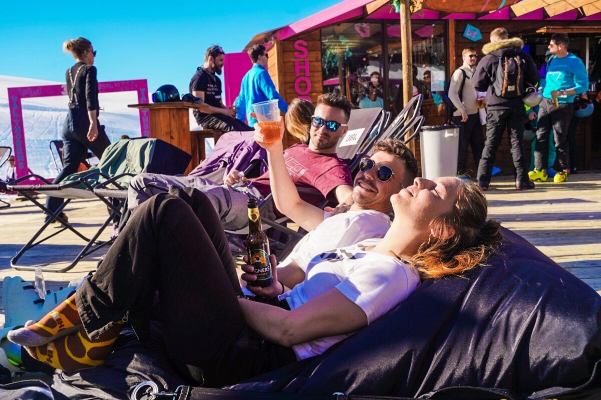 A woman laying on a bean bag chair holding a bottle of beer
