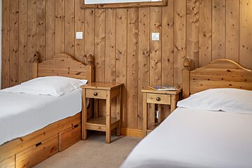 A bedroom with two beds and a nightstand with a book on it