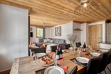 A dining table with plates and wine bottles on it