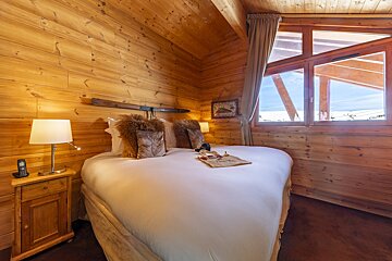 A wooden bedroom with a bed and a lamp