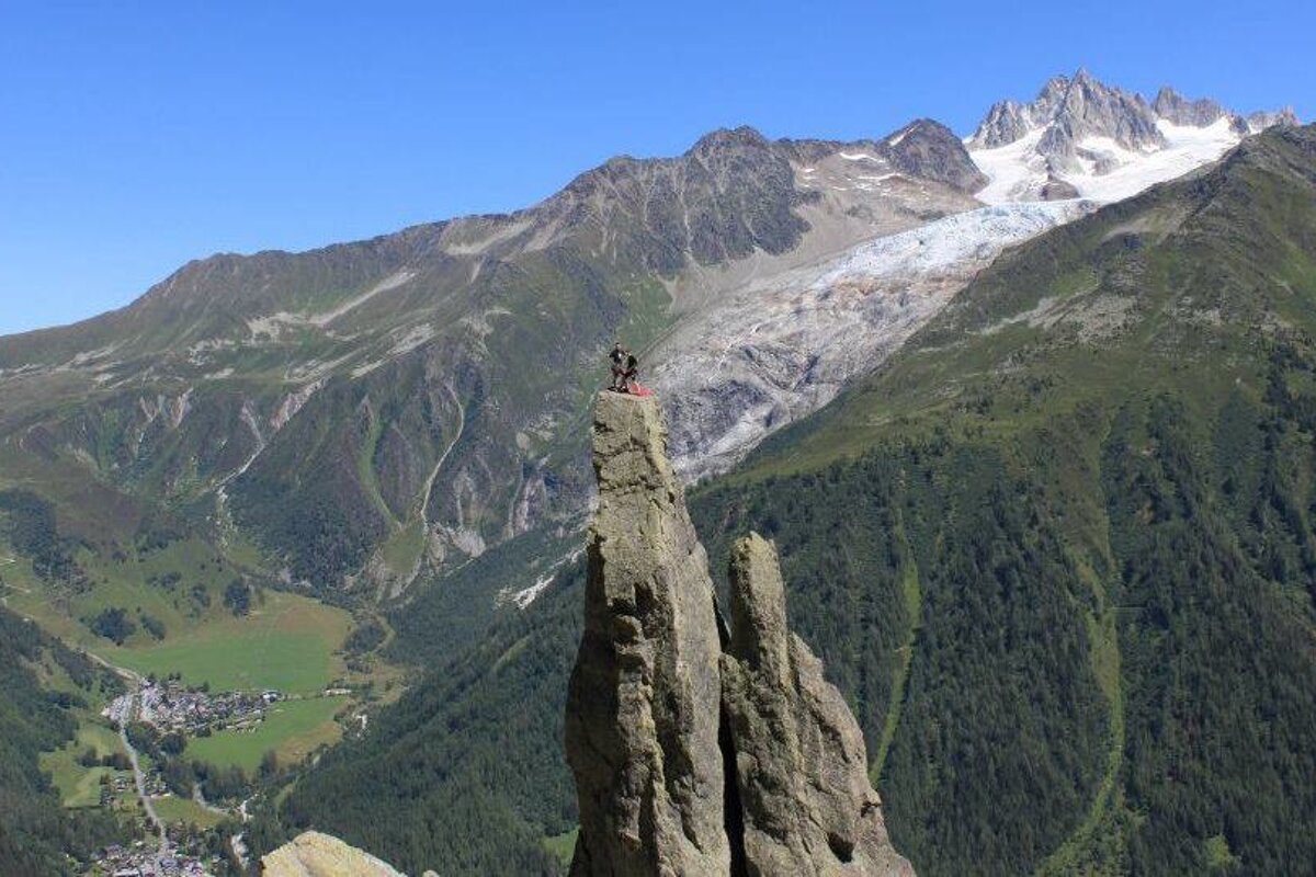 A person standing on top of a mountain with a glacier in the background